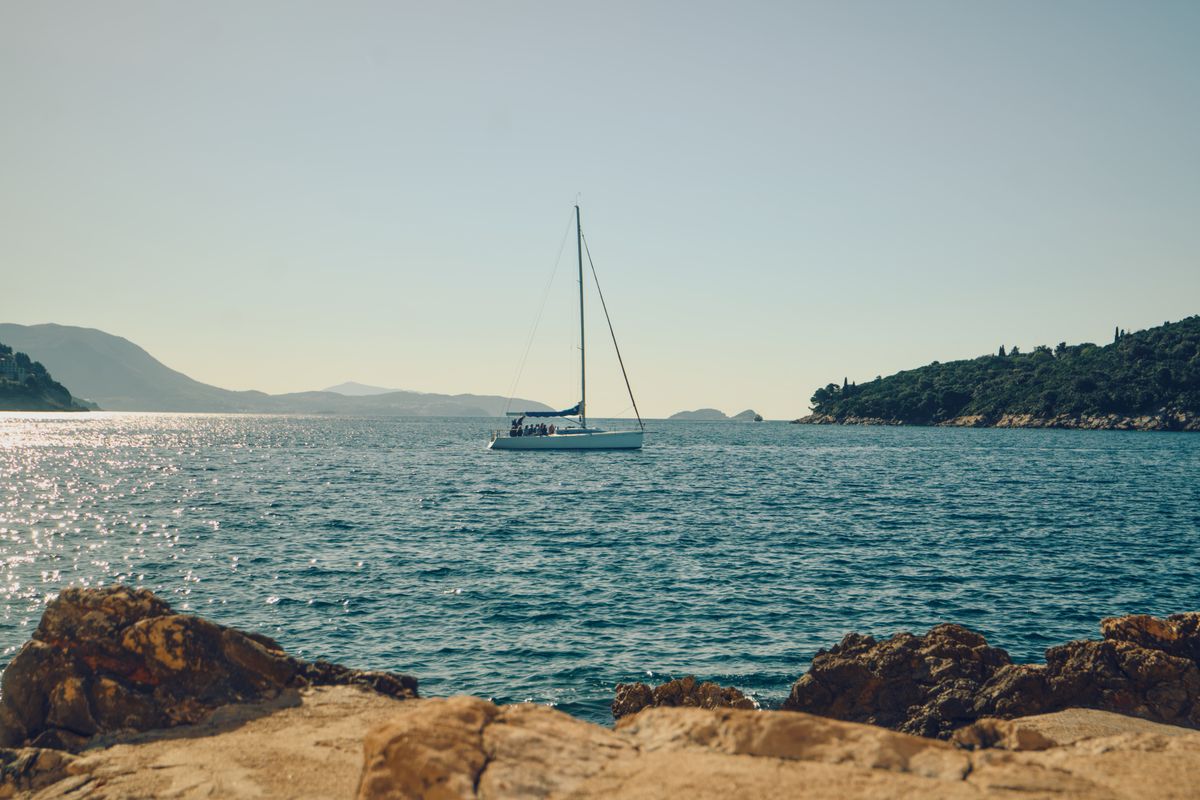 A luxury motor yacht gracefully navigating the clear blue waters between picturesque Croatian islands, perfect for an…